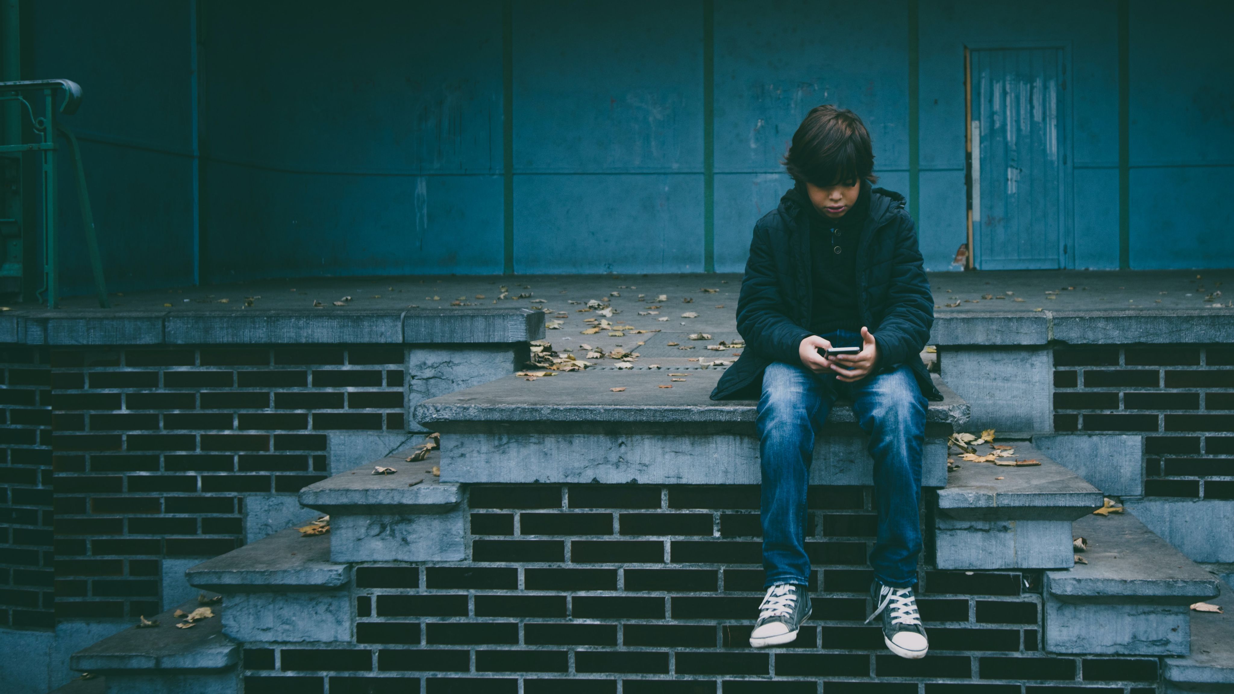 Child with smartphone sitting on wall